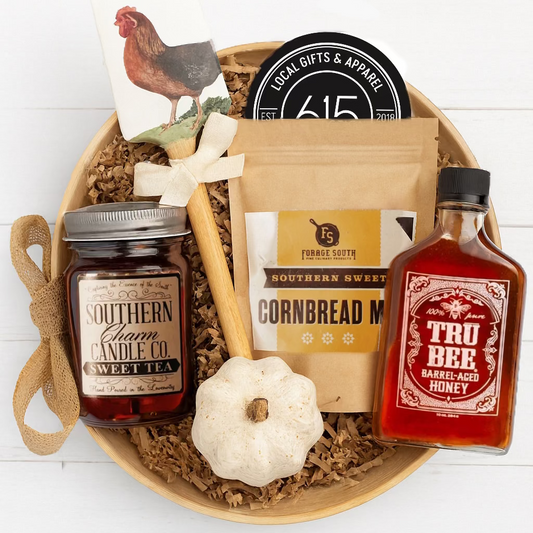 Gift basket with Southern Charm Candle Co. candle, cornbread mix, and Tru Bee honey on a white background